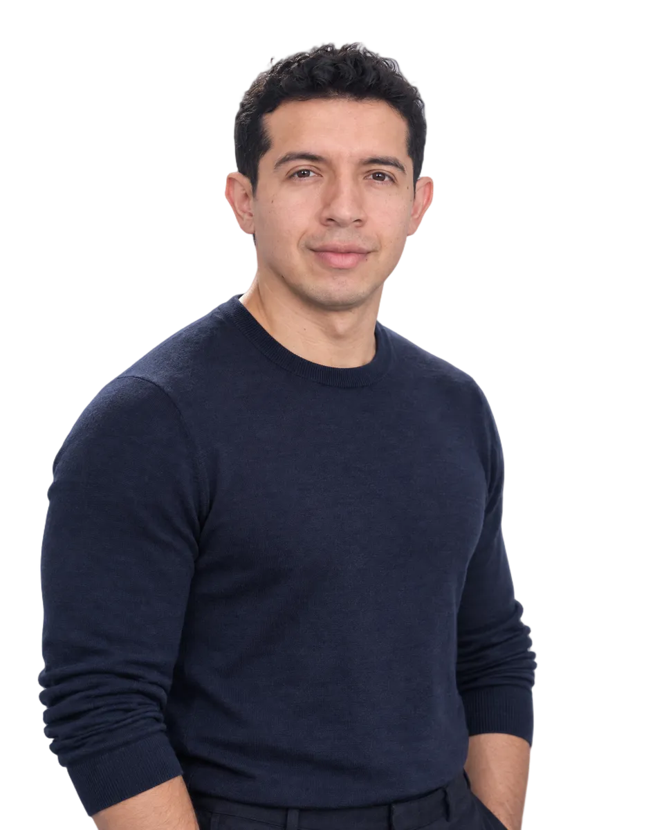 Alexander Ramírez, smiling, in a navy crew-neck sweater
